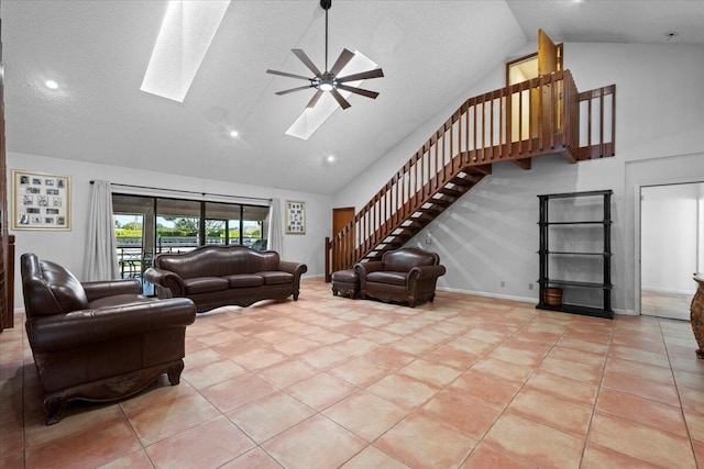 living area with a skylight, light tile patterned floors, baseboards, and stairs