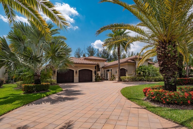 mediterranean / spanish house featuring a garage, a tile roof, decorative driveway, and stucco siding