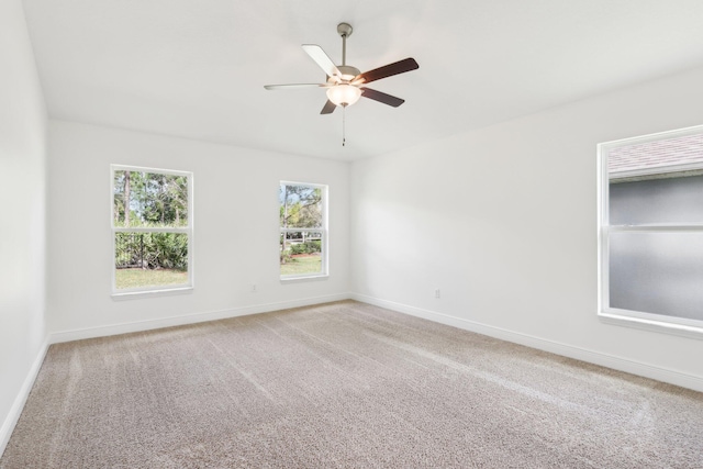 carpeted spare room with a ceiling fan and baseboards