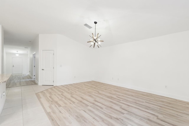 unfurnished room with baseboards, light wood-style floors, visible vents, and an inviting chandelier