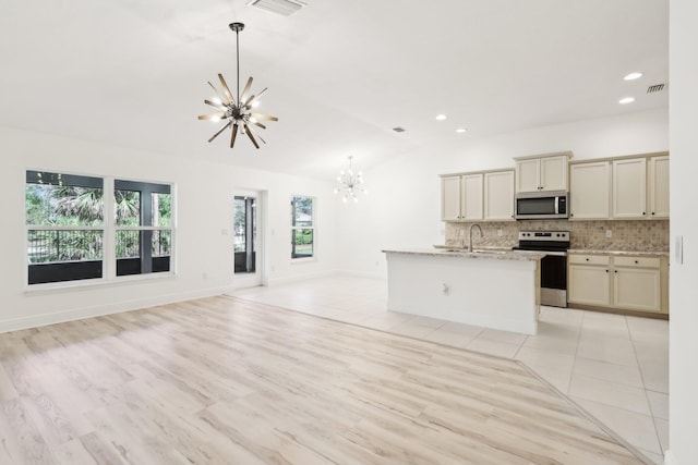 kitchen with decorative backsplash, open floor plan, stainless steel appliances, pendant lighting, and a notable chandelier