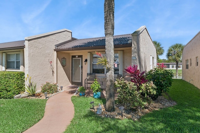 view of front of home featuring a tile roof, a front lawn, and stucco siding