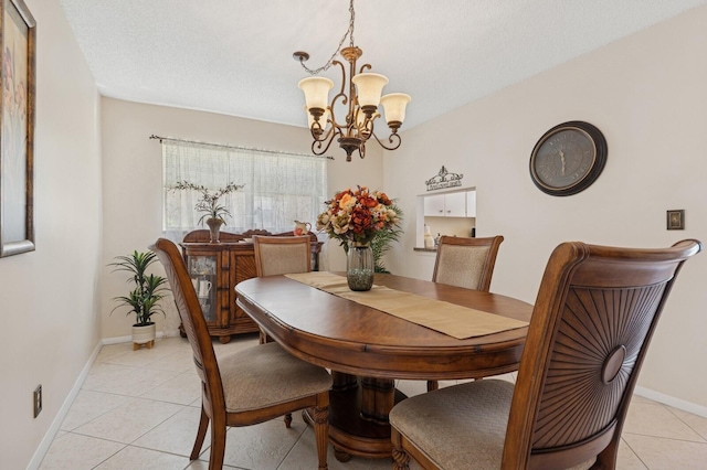 dining area with light tile patterned floors, a textured ceiling, baseboards, and a notable chandelier