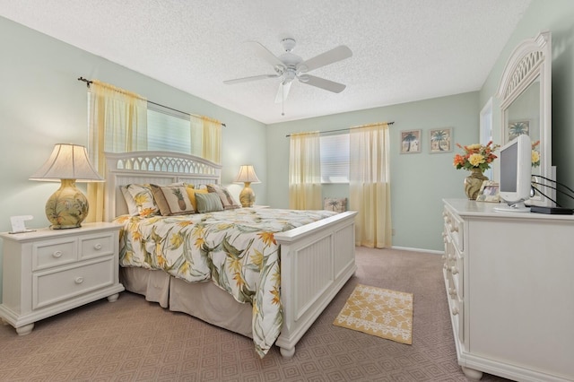 bedroom featuring ceiling fan, baseboards, a textured ceiling, and light colored carpet