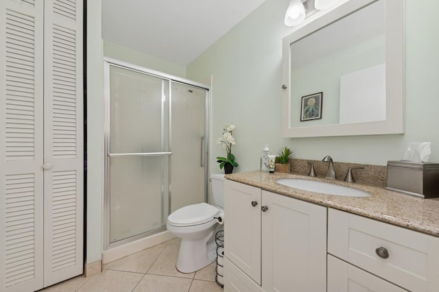 full bath with tile patterned flooring, toilet, vanity, a closet, and a stall shower