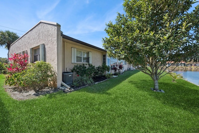 view of side of home with a yard, central AC unit, and stucco siding