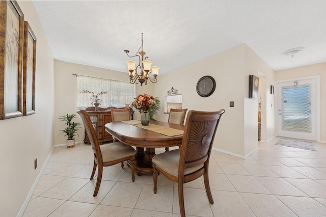 dining area with light tile patterned floors, baseboards, a textured ceiling, and an inviting chandelier