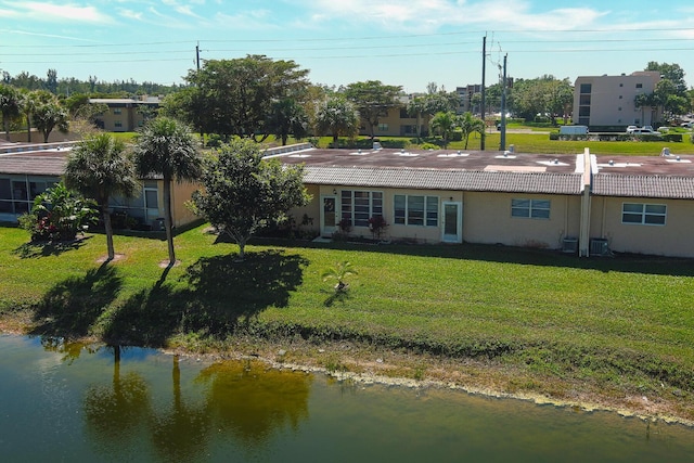 rear view of property featuring a lawn, a tiled roof, and stucco siding