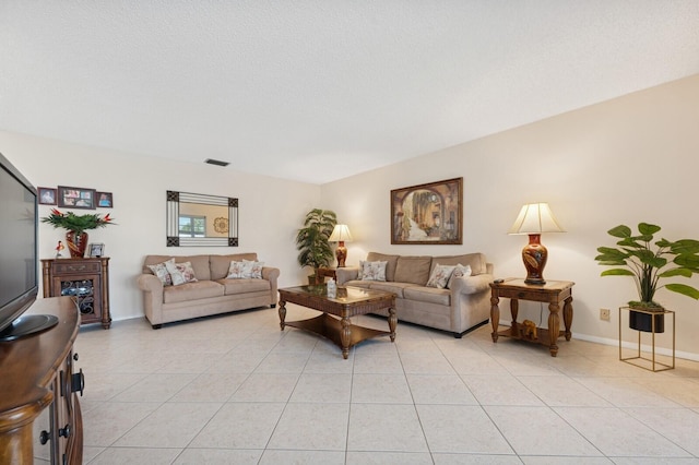 living area with light tile patterned floors, a textured ceiling, visible vents, and baseboards