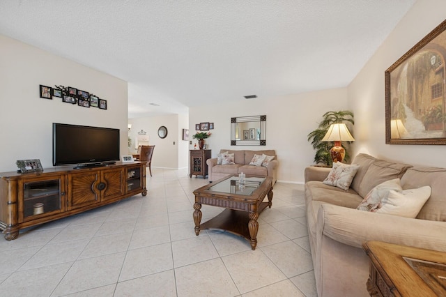 living room featuring visible vents, a textured ceiling, baseboards, and light tile patterned floors