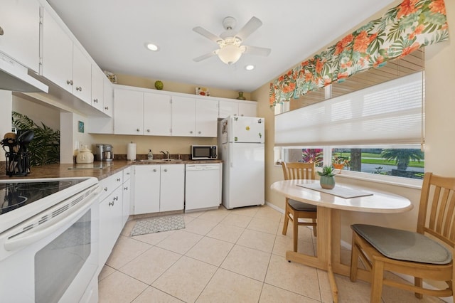 kitchen with light tile patterned floors, recessed lighting, white appliances, a sink, and white cabinets