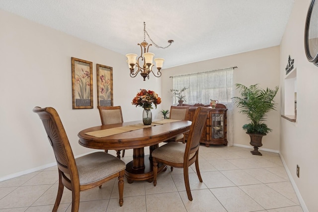 dining space with a chandelier, light tile patterned floors, a textured ceiling, and baseboards