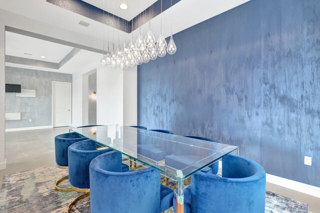 dining area featuring concrete flooring, a tray ceiling, visible vents, and baseboards