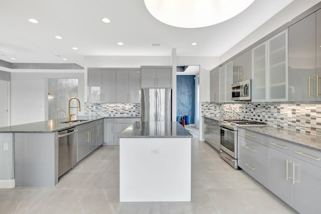 kitchen with modern cabinets, appliances with stainless steel finishes, a center island, gray cabinetry, and a sink