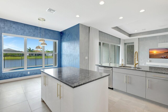 kitchen featuring visible vents, white cabinets, a kitchen island, stainless steel dishwasher, and a sink