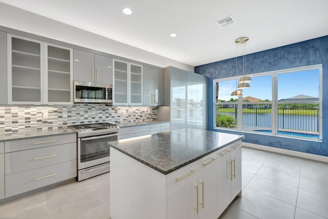 kitchen featuring visible vents, glass insert cabinets, gray cabinets, stainless steel appliances, and backsplash