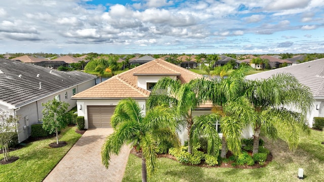 view of front of home featuring decorative driveway, a tile roof, stucco siding, an attached garage, and a residential view