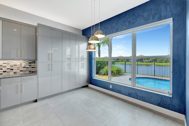 unfurnished dining area with light tile patterned floors, a water view, and baseboards