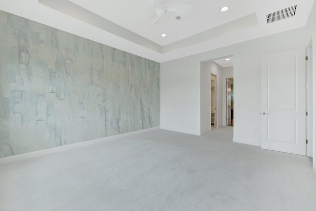 carpeted spare room featuring a tray ceiling, recessed lighting, visible vents, baseboards, and wallpapered walls