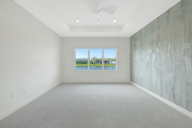 empty room with ceiling fan, recessed lighting, carpet floors, baseboards, and a tray ceiling