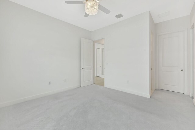 unfurnished bedroom with baseboards, ceiling fan, visible vents, and light colored carpet