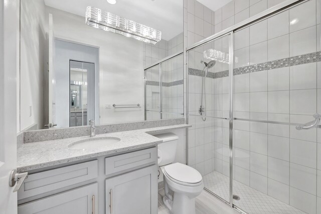 bathroom with toilet, a stall shower, and vanity