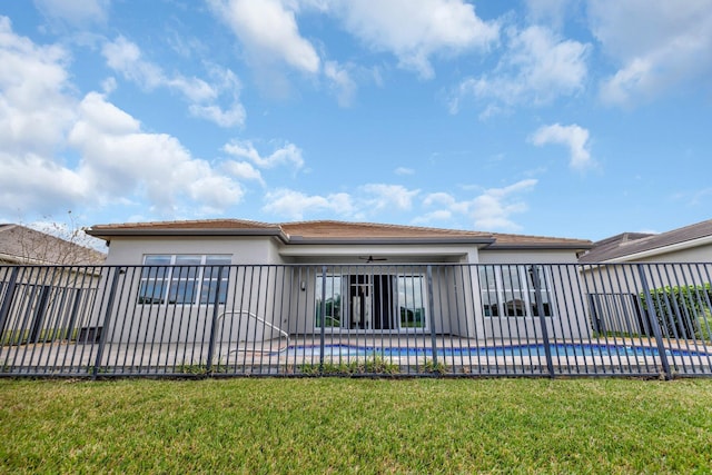 back of property with a lawn, fence, a fenced in pool, and stucco siding