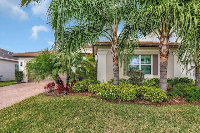 view of front of home featuring a garage, stucco siding, decorative driveway, and a front yard