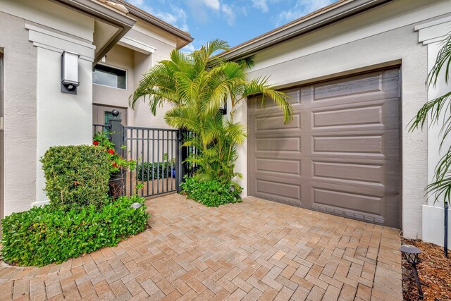 garage featuring decorative driveway and a gate