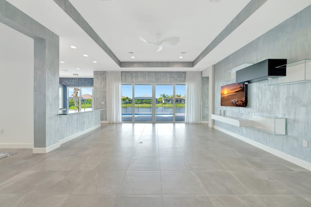 unfurnished living room with tile patterned flooring, a healthy amount of sunlight, and baseboards