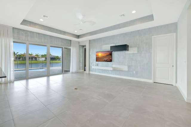 unfurnished living room featuring wallpapered walls, visible vents, baseboards, and a raised ceiling