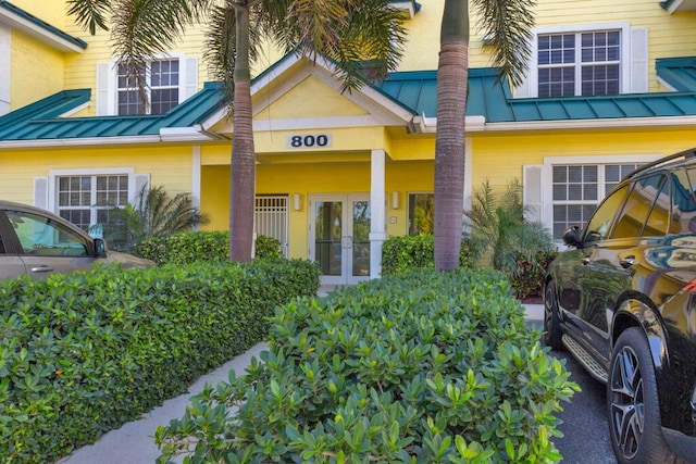 property entrance featuring a standing seam roof, metal roof, and french doors