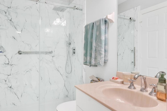 full bathroom featuring toilet, a marble finish shower, and vanity