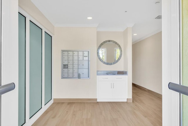 interior space featuring light wood-style floors, crown molding, and mail area