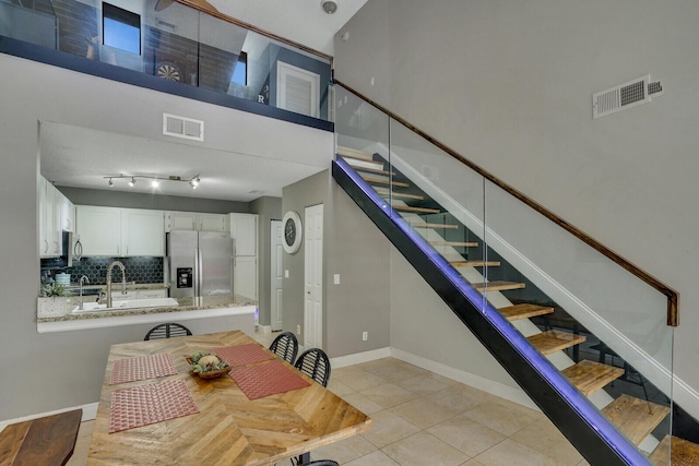 staircase featuring baseboards, visible vents, a high ceiling, and tile patterned floors