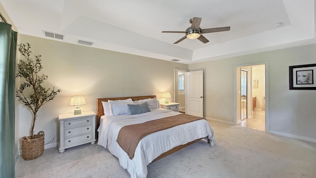 bedroom with baseboards, visible vents, a raised ceiling, and light colored carpet