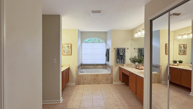 full bathroom with two vanities, tile patterned flooring, a garden tub, and a textured ceiling