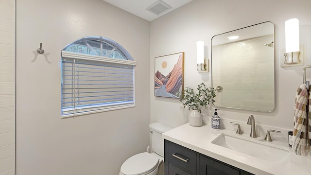 bathroom featuring visible vents, vanity, a tile shower, and toilet