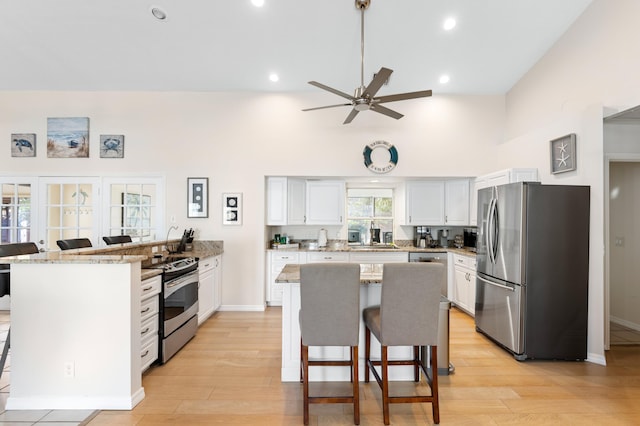 kitchen with a peninsula, light wood-style floors, stainless steel appliances, and a kitchen breakfast bar