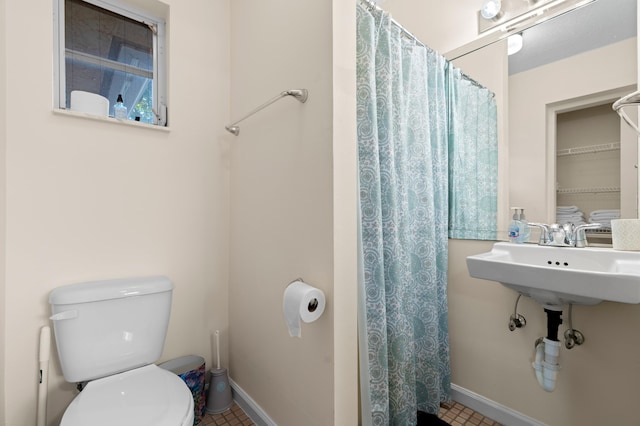 full bathroom featuring curtained shower, baseboards, a sink, and toilet