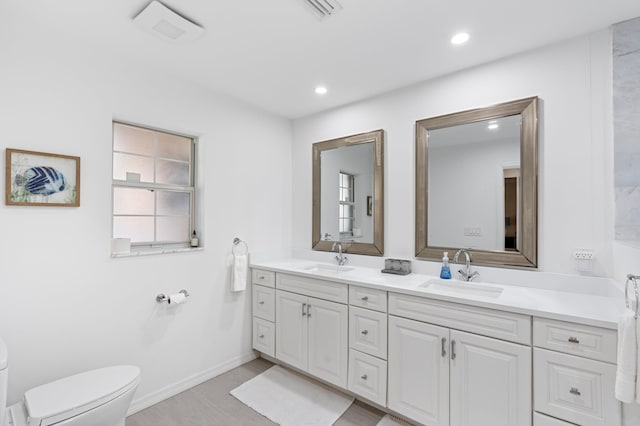 full bathroom with double vanity, a sink, toilet, and recessed lighting