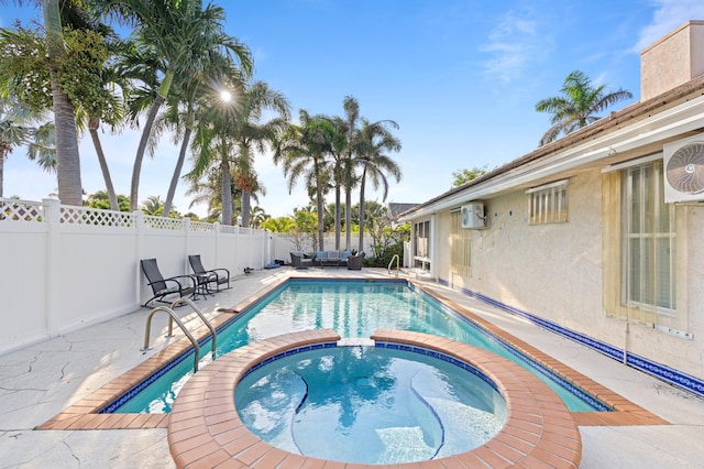 view of pool with an AC wall unit, a patio area, a fenced backyard, and a pool with connected hot tub