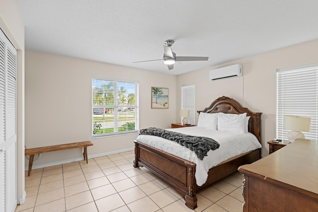 bedroom featuring light tile patterned floors, a wall mounted AC, a ceiling fan, and baseboards