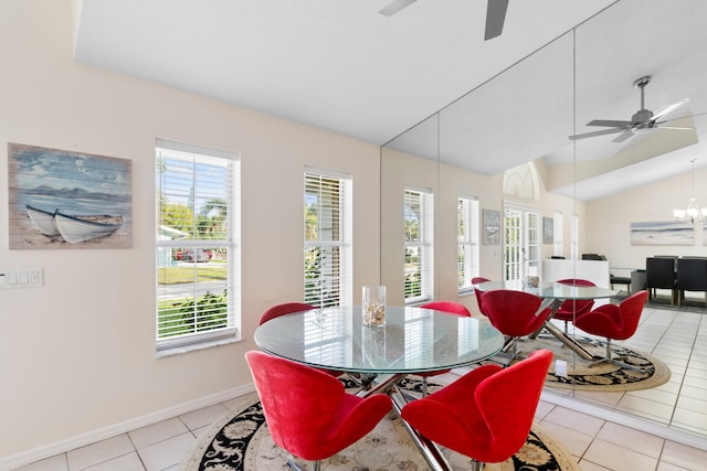 dining space with vaulted ceiling, ceiling fan with notable chandelier, light tile patterned flooring, and baseboards