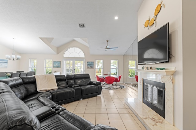 living room with lofted ceiling, visible vents, an inviting chandelier, a premium fireplace, and light tile patterned flooring