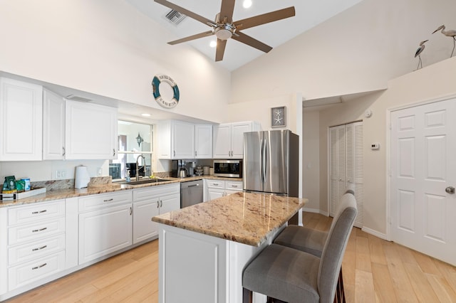 kitchen featuring visible vents, white cabinets, a breakfast bar area, appliances with stainless steel finishes, and a sink