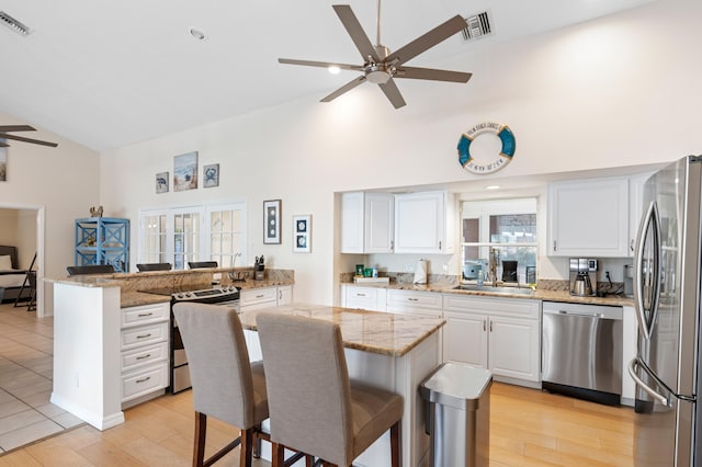 kitchen featuring visible vents, a ceiling fan, stainless steel appliances, a kitchen bar, and a sink