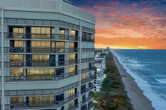 property at dusk featuring a beach view and a water view