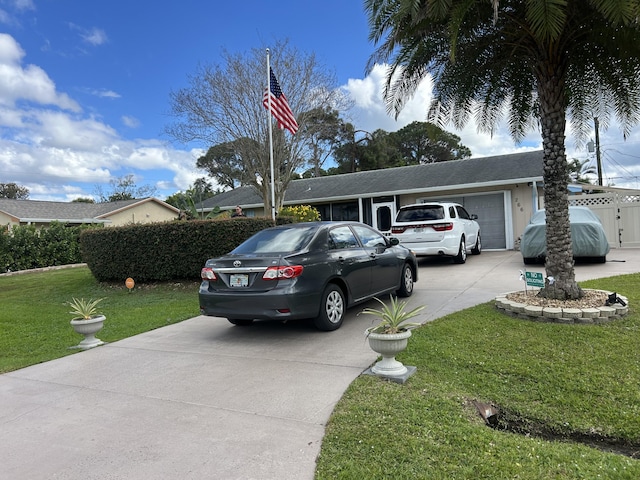 view of front of property with a front yard, concrete driveway, and an attached garage