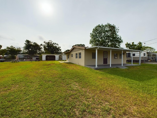 rear view of property with a lawn, a patio area, and stucco siding